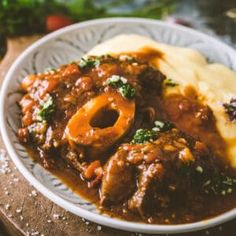 a white plate topped with meat and gravy next to mashed potatoes