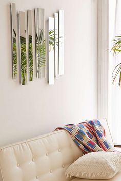 a white couch sitting under three mirrors in a living room