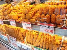 many different kinds of fried food on display in a grocery store's deli