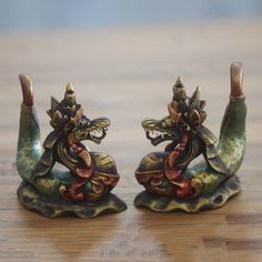 two small figurines sitting on top of a wooden table