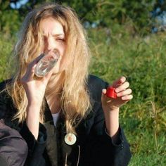 a woman sitting in the grass drinking from a bottle