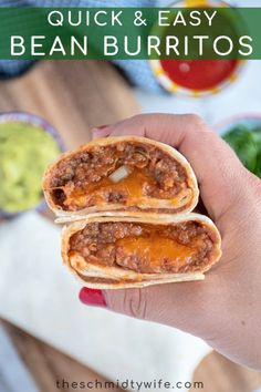 two burritos are being held up in front of some guacamole