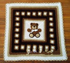 a crocheted square with a teddy bear in the center on a wooden floor