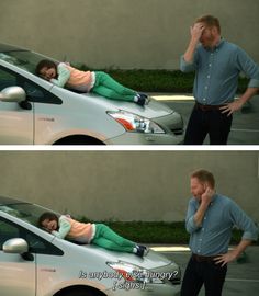 a man talking on the phone next to a woman laying on top of a car