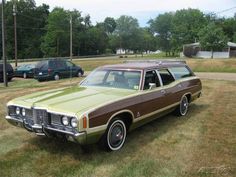 a brown and tan station wagon parked in a field next to other cars on the grass