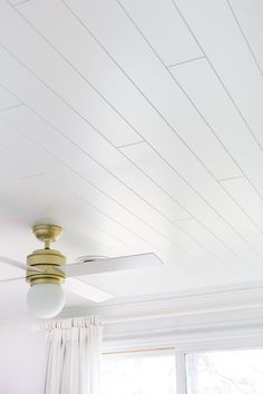 a ceiling fan in a room with white walls and wood trimmings on the ceiling