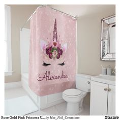 a pink shower curtain with an unicorn's face and flowers on it, sitting next to a toilet