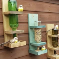 three wooden bird feeders with birds perched on them