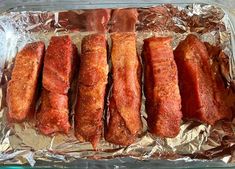 four pieces of meat are on tinfoil in the oven, ready to be cooked