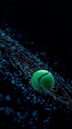 a green tennis ball floating in the air with water droplets on it's surface