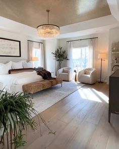 a bedroom with a bed, chairs and a chandelier hanging from the ceiling