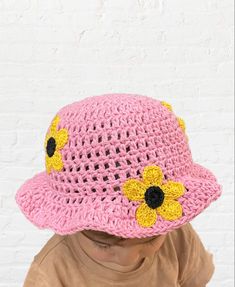 a child wearing a pink crocheted hat with yellow flowers