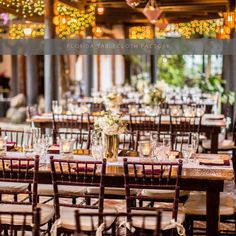 tables and chairs are set up for an outdoor event with lights hanging from the ceiling