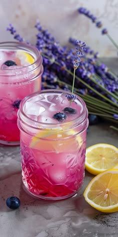 two mason jars filled with lemonade and blueberries sitting next to lavender sprigs