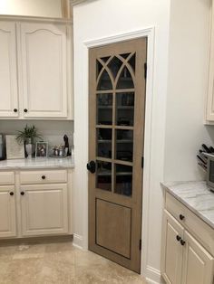 a kitchen with white cabinets and an arched glass door in the center, along with marble counter tops