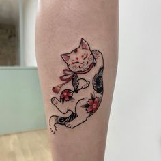 a cat tattoo is on the leg of a woman's legs, with flowers around it