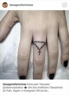 a woman's hand with a small cross tattoo on the middle finger and black ink