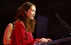 a woman standing at a podium in front of a microphone