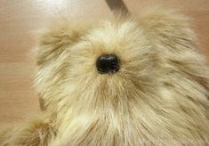 a brown teddy bear sitting on top of a wooden floor