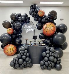 an arrangement of balloons and basketballs are displayed in the center of a room with a sign that says happy birthday