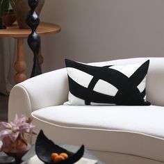 a black and white pillow sitting on top of a couch next to a vase with flowers