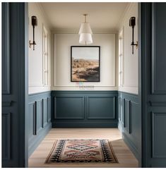 an empty hallway with blue painted walls and wood flooring, framed artwork on the wall