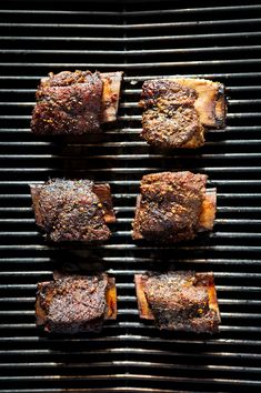 four pieces of meat sitting on top of a grill