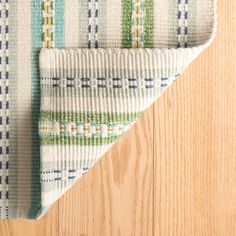 a close up of a rug on a wooden floor with a white and blue pattern