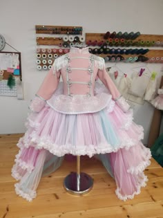 a mannequin dressed in pink, blue and white tulle skirt sitting on top of a wooden table