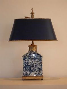 a blue and white vase sitting on top of a table next to a black lamp