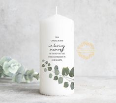 a white candle with greenery on it and the words, this conquering is being memory