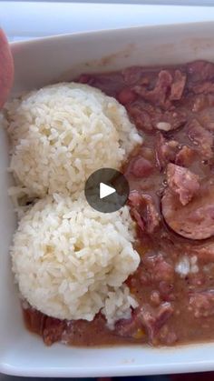 a person is holding a plate with rice and meat in it, which includes beans