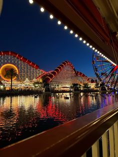 an amusement park at night with lights reflecting in the water