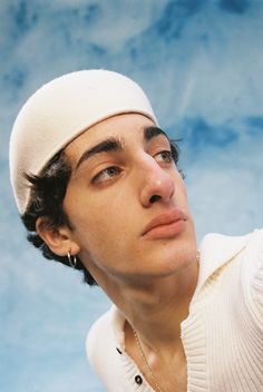 a young man wearing a white hat and sweater