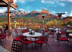 an outdoor dining area with red chairs and mountain view in the backgroung