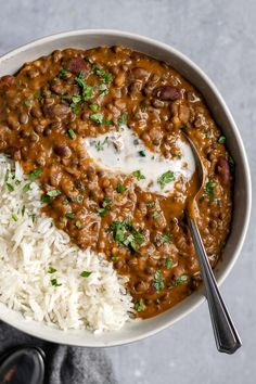 a bowl filled with rice and beans next to a spoon on top of a table