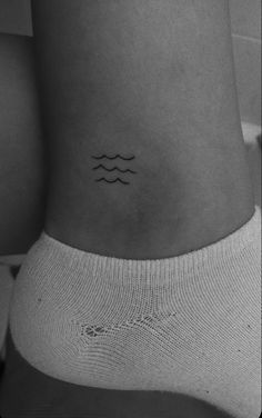 a black and white photo of a woman's stomach with waves tattoo on it