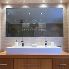 a bathroom sink with two soap dispensers in front of a large mirror