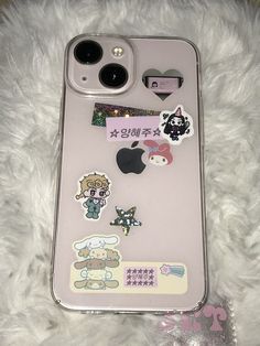 an iphone case with various stickers on it sitting on top of a white furry surface