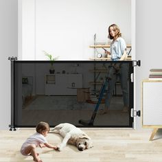 a woman and child playing with a dog in front of a screen door that is open