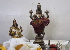 a silver statue sitting on top of a white table next to other statues and cloths