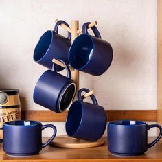 blue coffee mugs stacked on top of each other in front of a wooden shelf