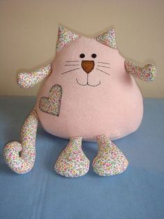 a pink cat stuffed animal sitting on top of a blue tablecloth covered bedding