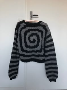 a black and white sweater hanging on a door