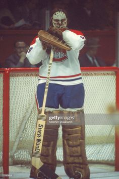 an ice hockey goalie standing in front of the net with his hands on his hips