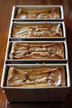 four pans filled with brownies sitting on top of a wooden table