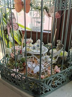 a birdcage filled with miniature furniture and flowers