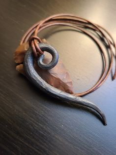 a piece of metal sitting on top of a wooden table next to a brown cord