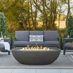 an outdoor fire pit sitting on top of a patio next to chairs and tables with pillows