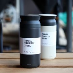 two travel tumblers sitting on top of a wooden table